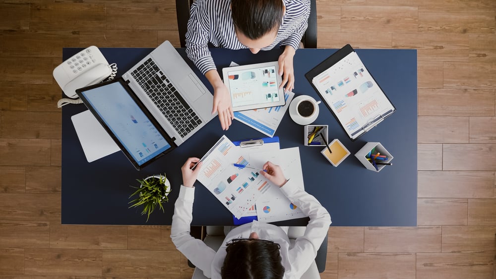 Top view of business women comparing financial graphs with management statistics expertise discussing company strategy working in startup office. Corporate directors brainstorming economy ideas